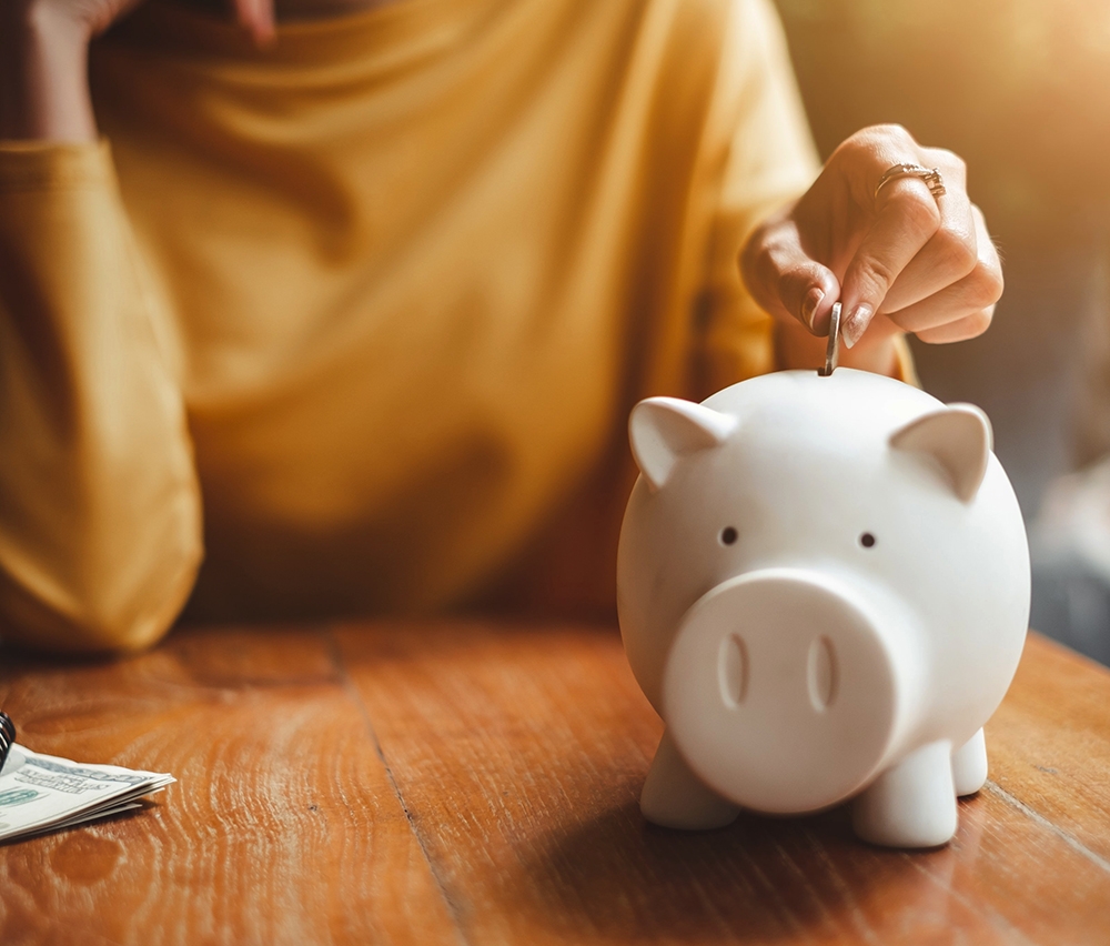 person inserting coin into piggy bank